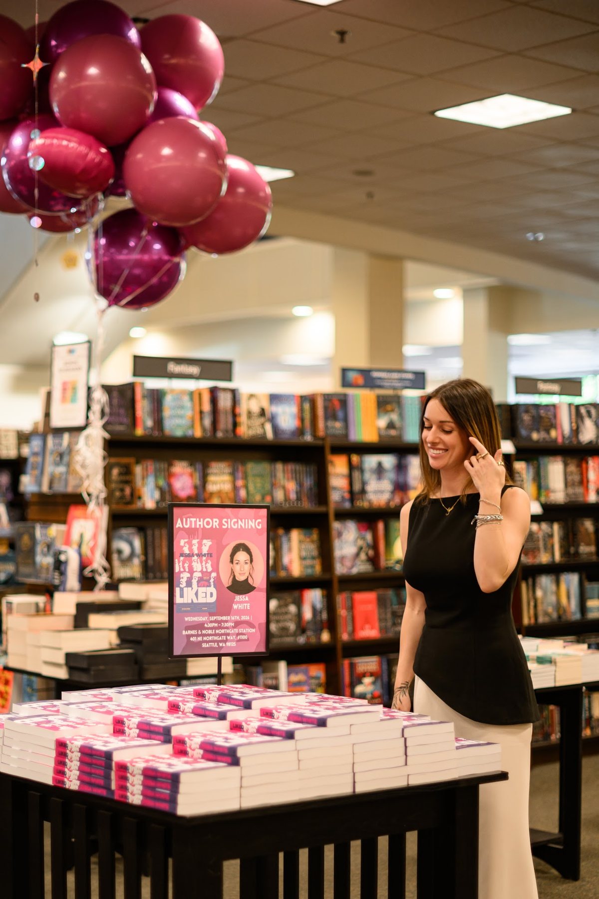 Jessa beside the signing table stacked with copies of Liked